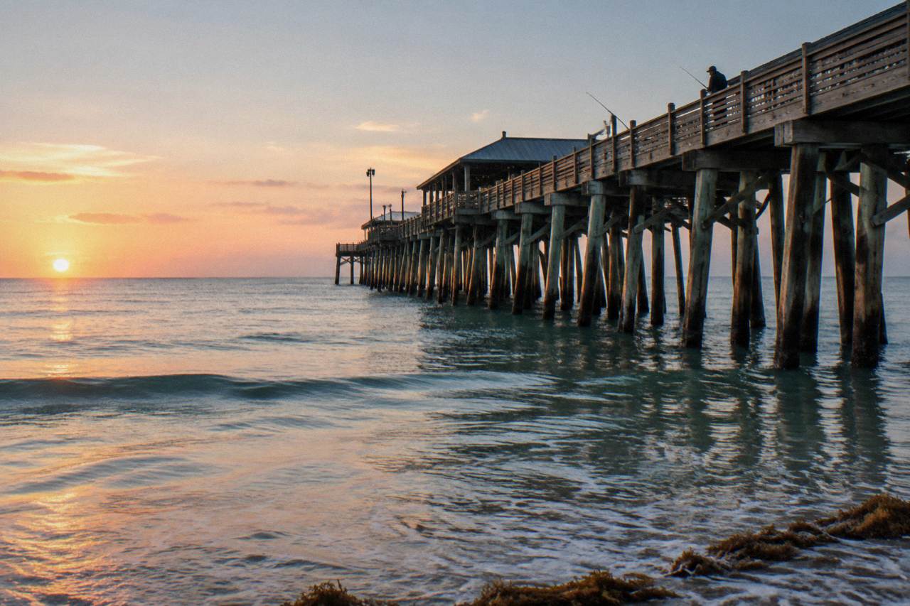 Wooden fishing pier extending over calm Atlantic water at Cocoa Beach